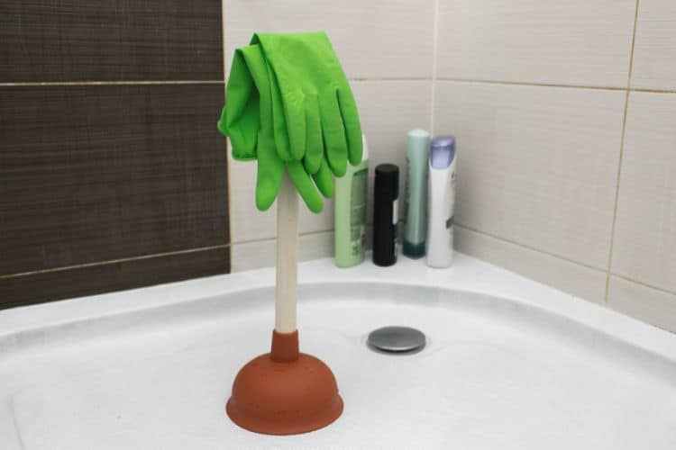 plunger and pair of gloves in shower tray
