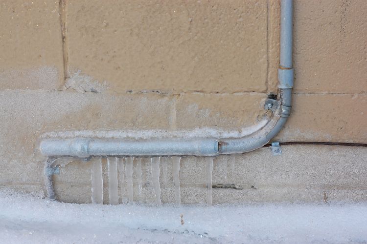 External pipe on wall frozen with icicles formed underneath