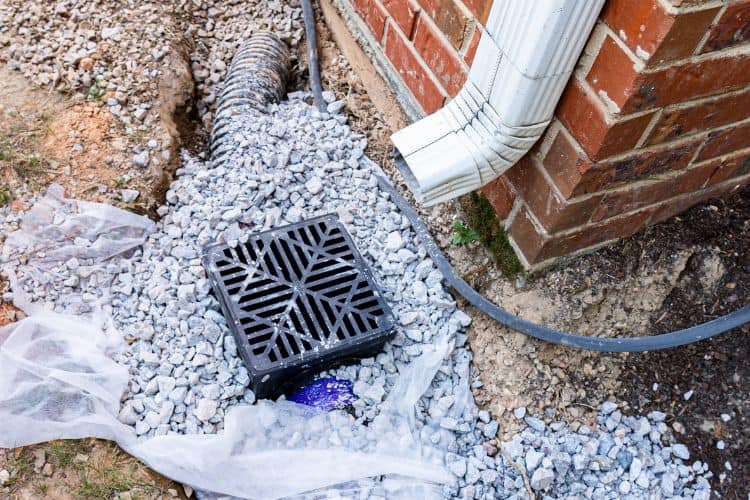 Plastic catch basin installed under a downspout pipe