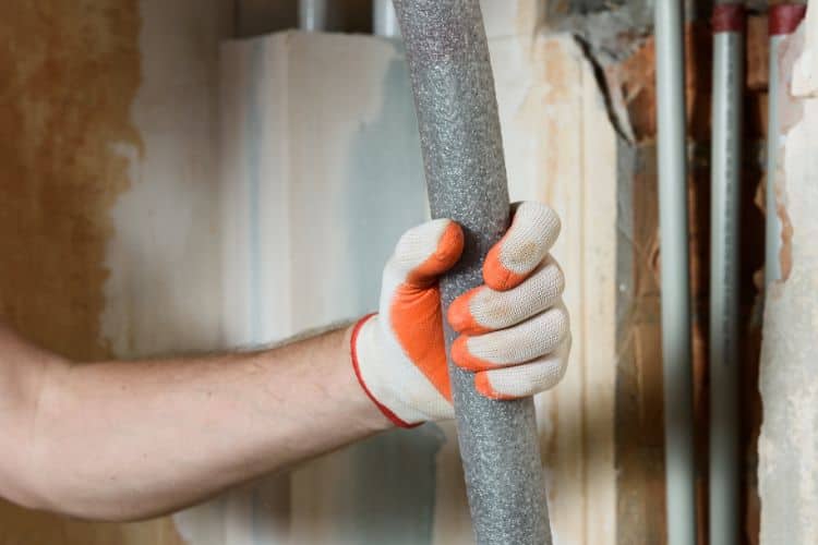 Plumber holding foam thermal insulation for covering home water pipes