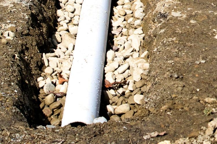 Trench dug and infilled with gravel for french drain installation