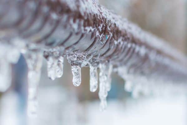 Close up of a frozen pipe with icicles hanging down