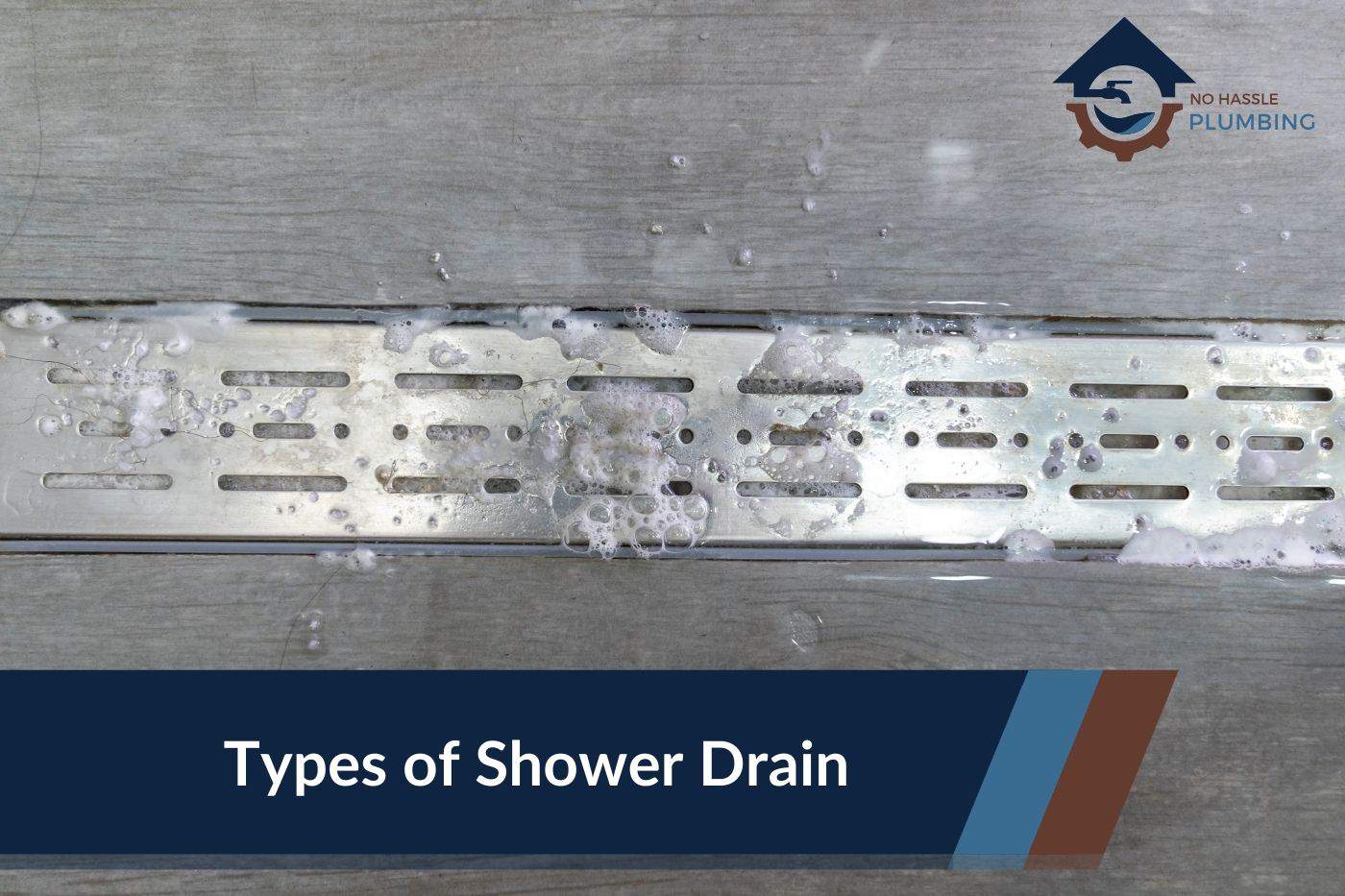 Types of Shower Drains - No Hassle Plumbing.com Featured Image of a Linear Shower Drain with soap bubbles and water lying in pools around it.
